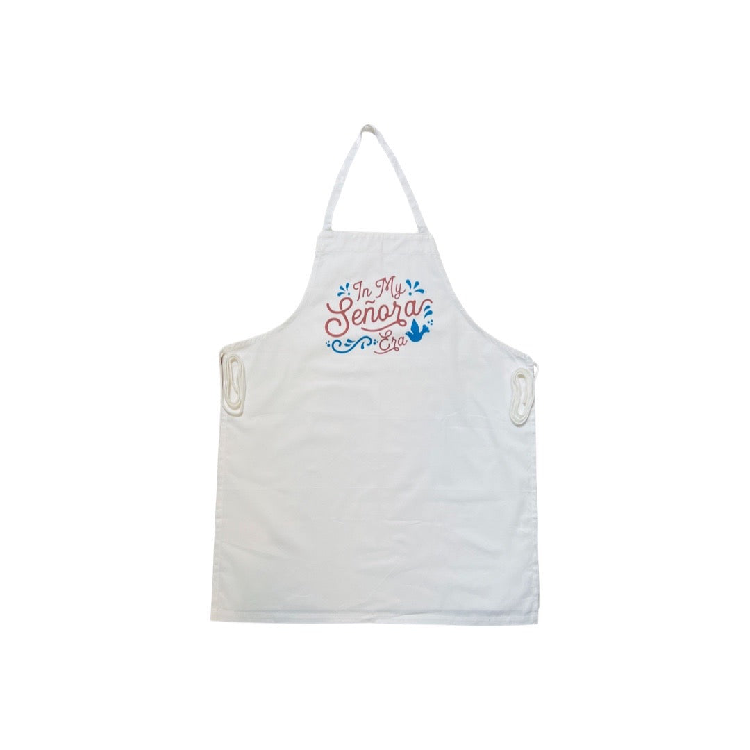 white apron with the phrase In My señora era in brown lettering and features a blue bird and filagree