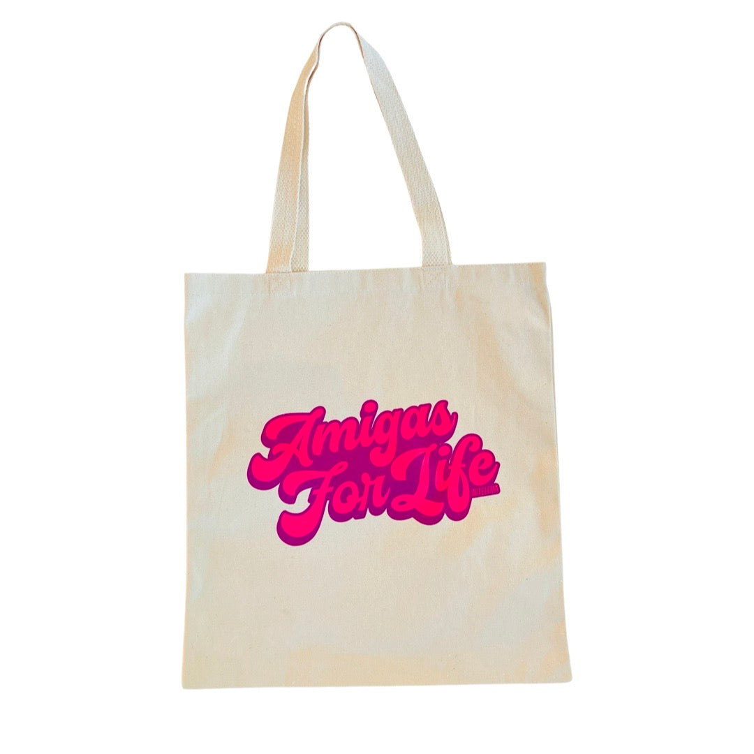 Natural tote bag with the phras Amigas for Life in hot pink lettering outlined in fuschia.