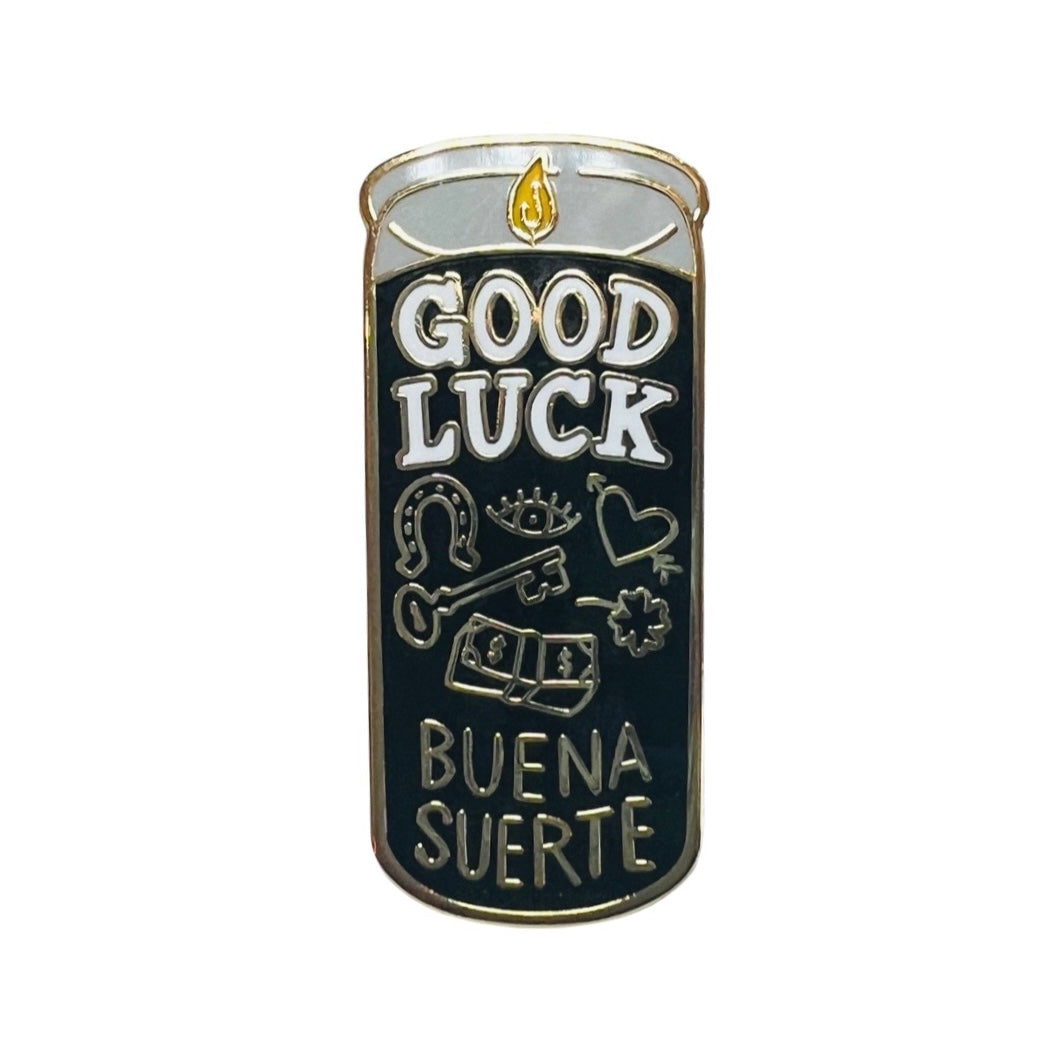 Black candle enamel pin with images of a horse shoe, key, heart, four-leaf clover and money with the phrases Good Luck and Buena Suerte.