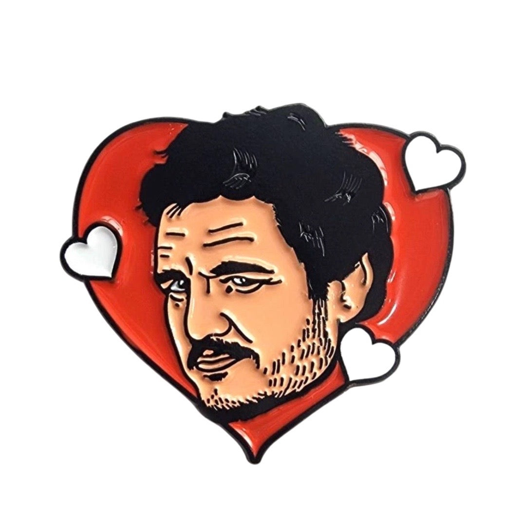 A red heart enamel pin with an image of Pedro Pascal with three white hearts.