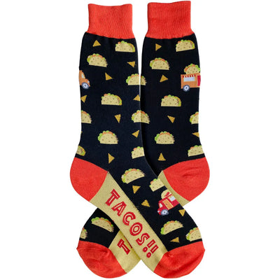 Black men’s socks with a repeating taco, chip, and taco truck pattern, red heels, toes, and cuffs, and “TACOS!!” text on the sole.