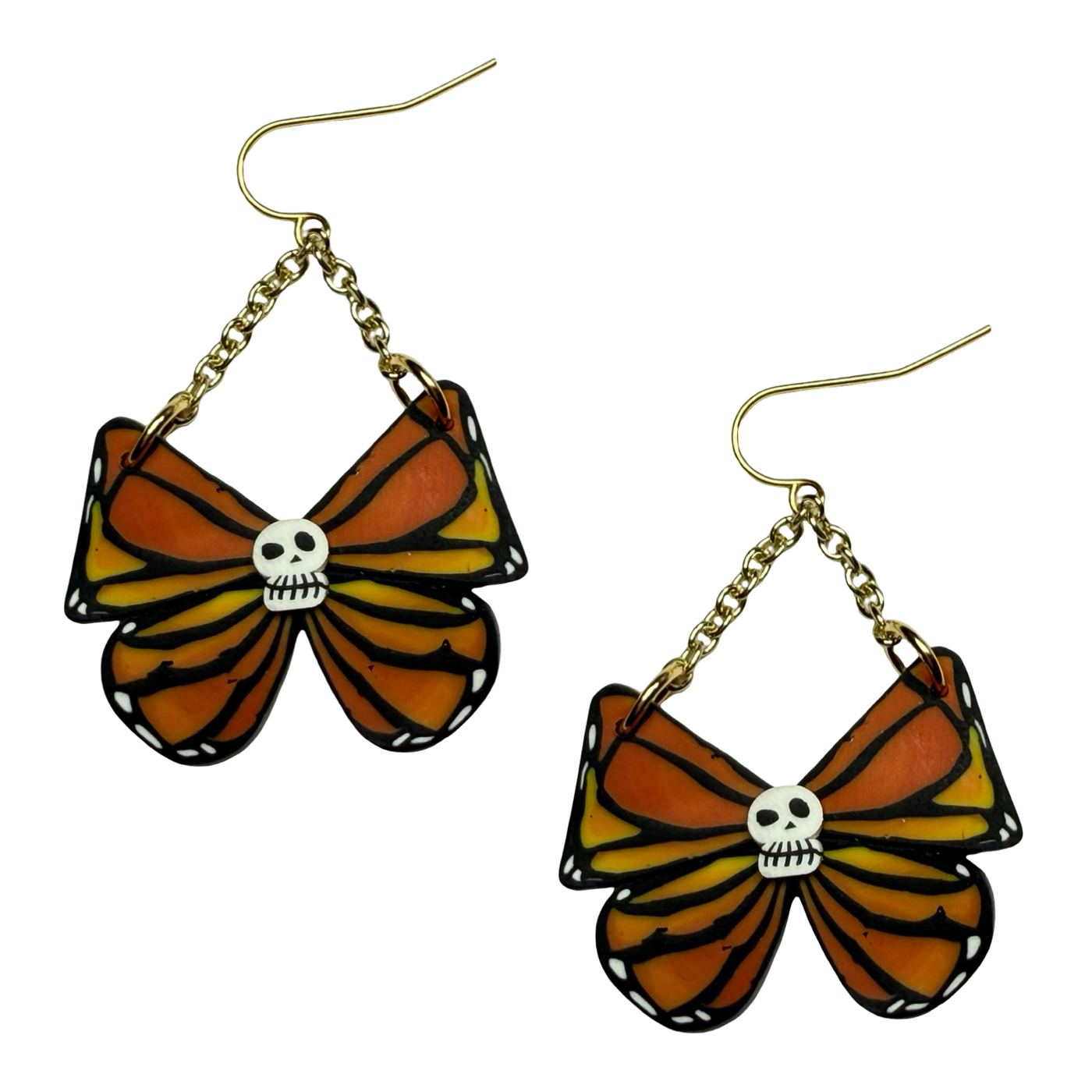 Butterfly-shaped earrings with skull designs on a white background