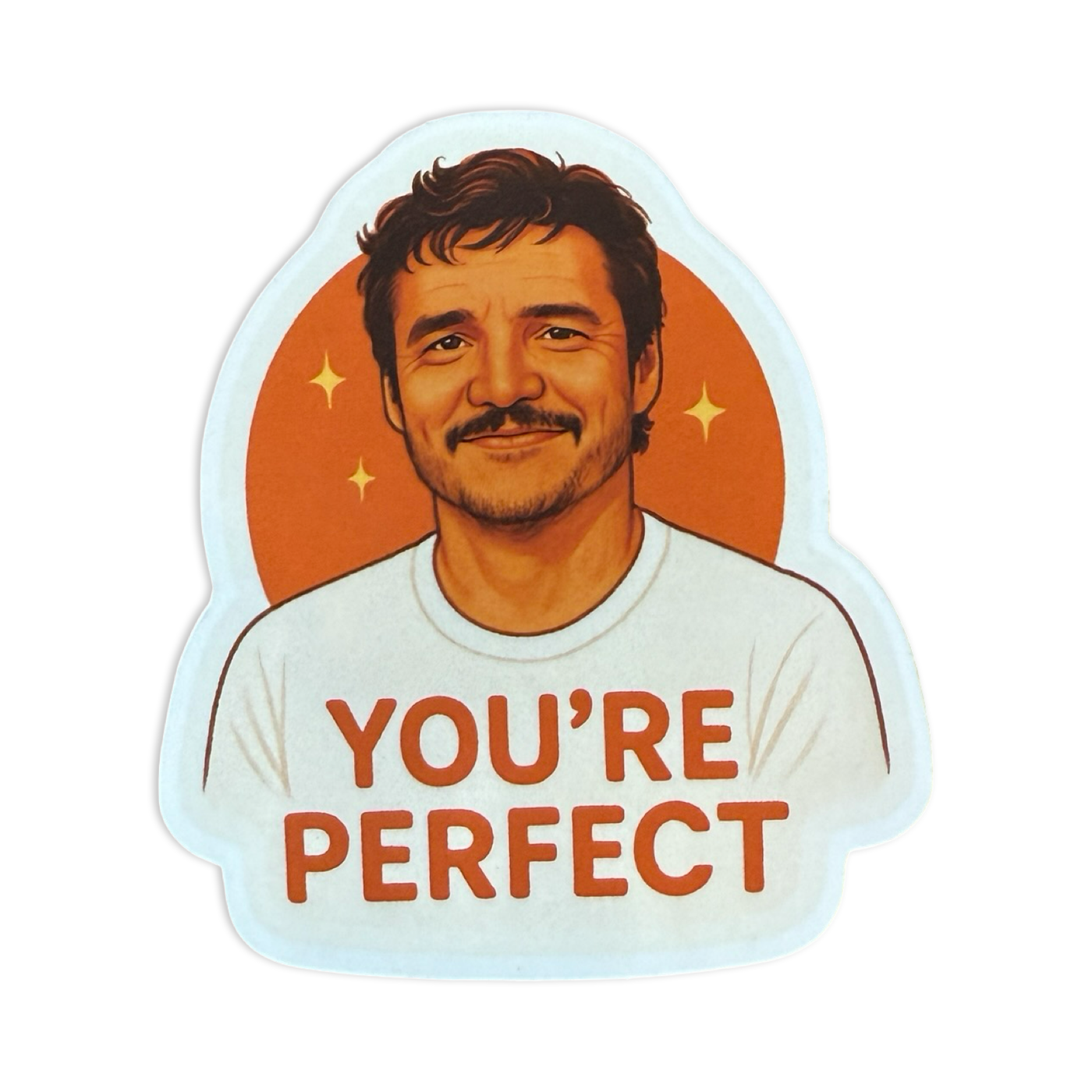 Sticker of a smiling Pedro with tousled hair in a white t-shirt that says “YOU’RE PERFECT,” set against a warm orange background with sparkles.