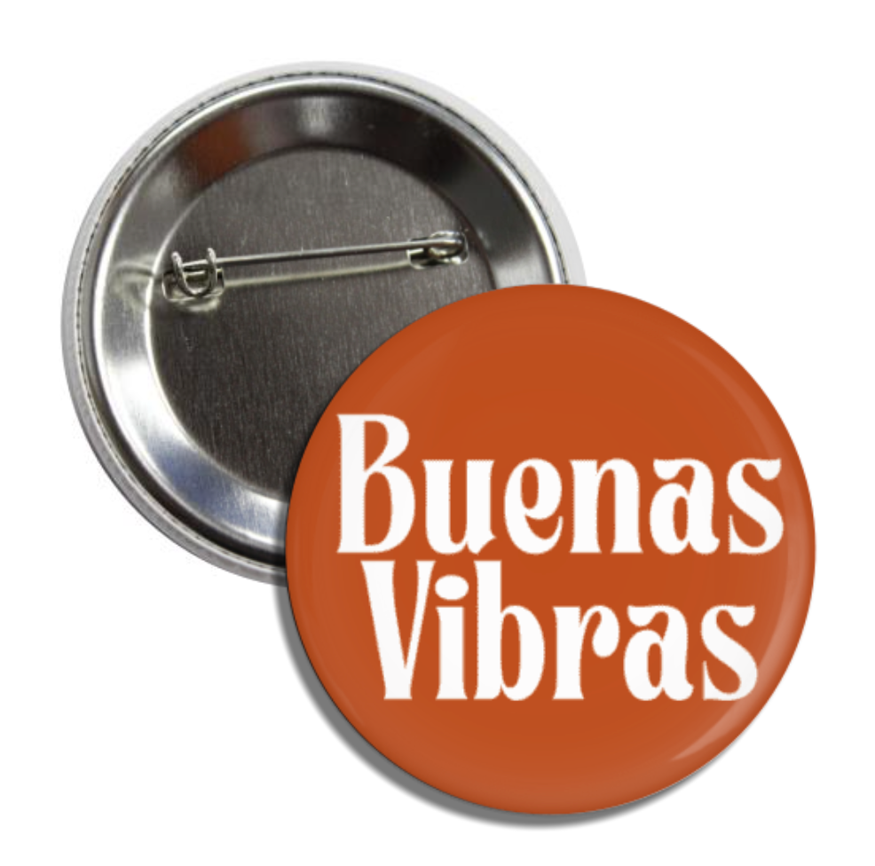 Round pin back button with a terra cotta background & phrase Buenas Vibras in white lettering