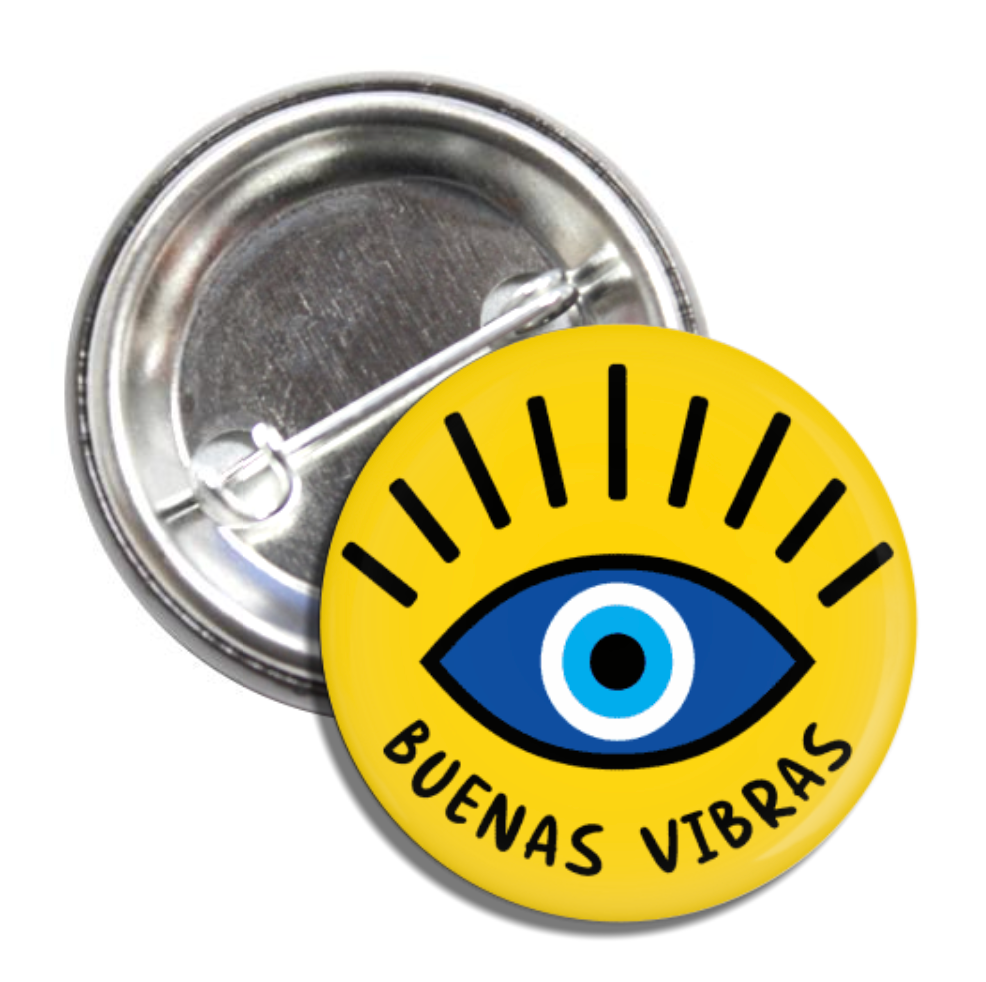 Round pin back button with a yellow background, an evil eye and the phrase buenas vibras in black lettering