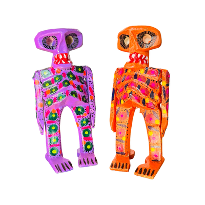 set of Colorful hand-painted wooden sugar skull skeleton figures in purple and orange with decorative patterns.