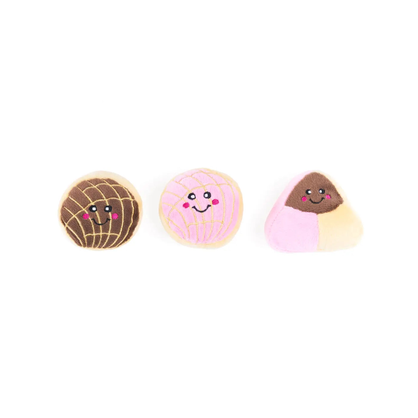 three mini pan dulce plush dog toys. One brown concha, one pink concha and one payaso pan dulce all with smiley faces.