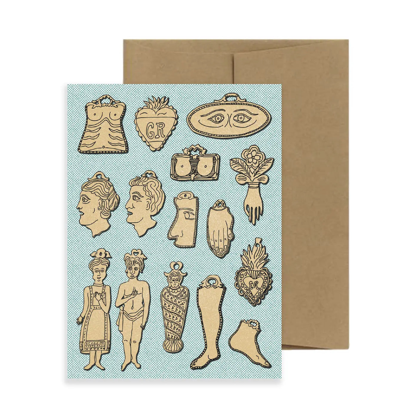 A greeting card featuring gold milagro illustrations on a textured blue background, depicting symbolic charms like hearts, hands, eyes, faces, and limbs. The card is accompanied by a brown kraft envelope.