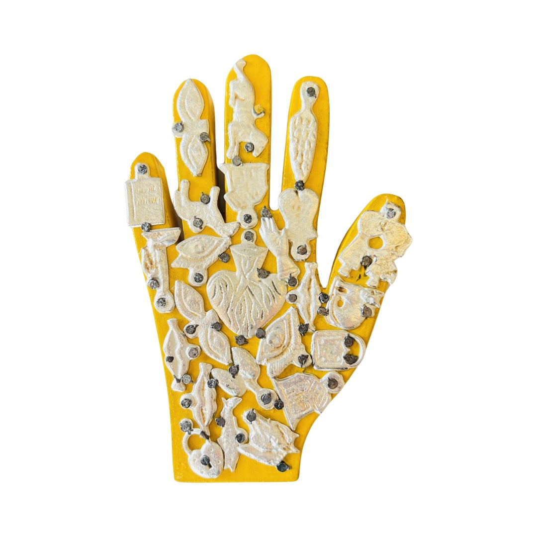 Handmade wooden milagro hand in yellow. Design features a variety of mini milagro charms.