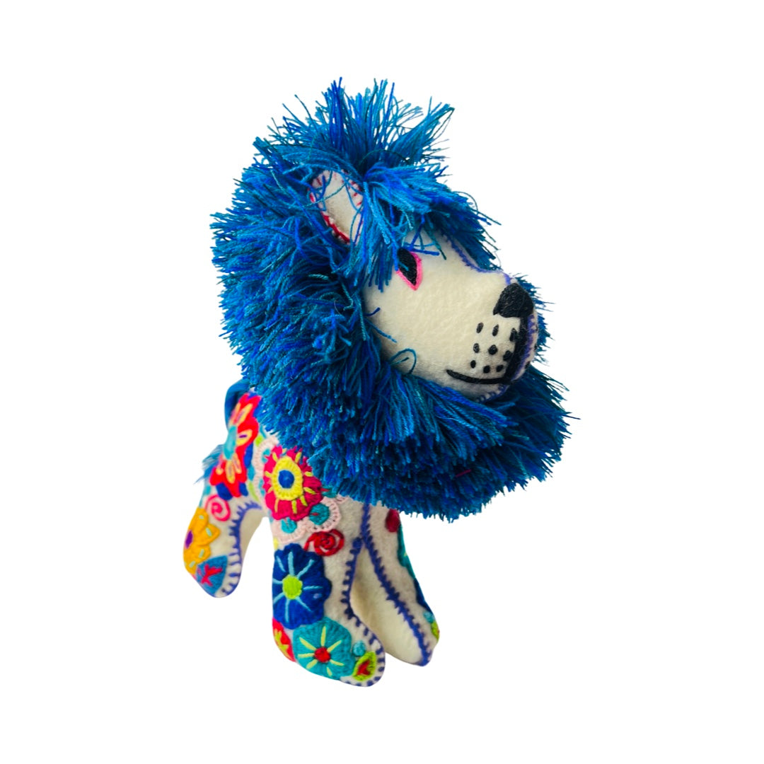 side view of a white embroidered lion with a blue mane and features colorful flowers.
