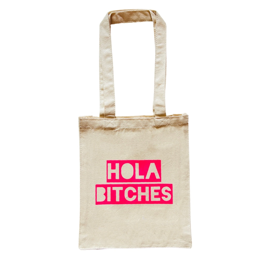 Natural tote bag with the phrase Hola Bitches in pink lettering.
