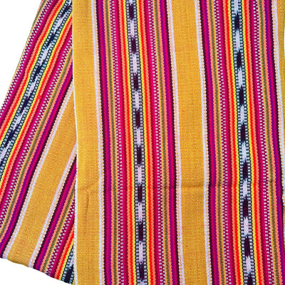 Close up view of A handwoven throw blanket with stripes of rusty straw, pinks, and greens folded in quarters