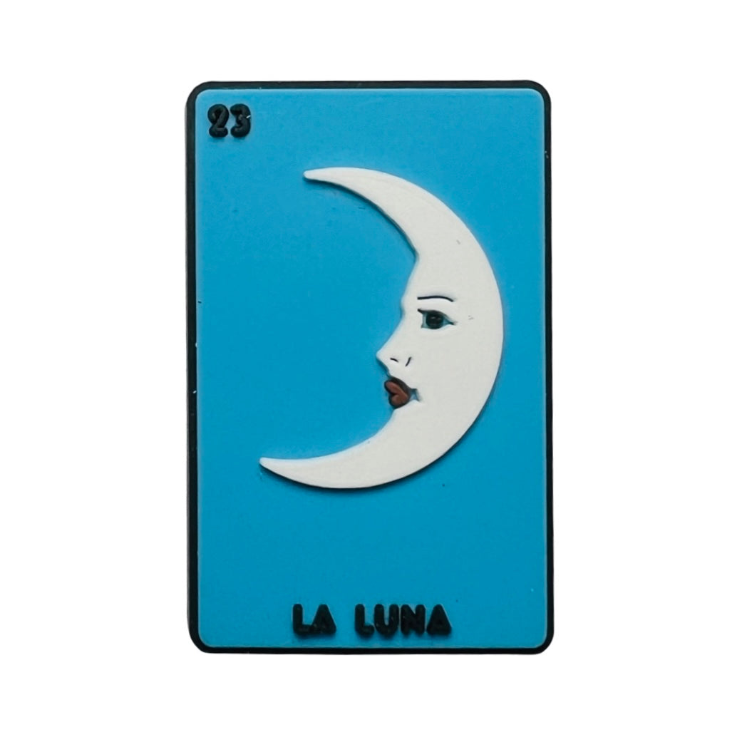 Rubber La Luna loteria chancla, croc, charm featuring a blue background with a white half moon with a face.