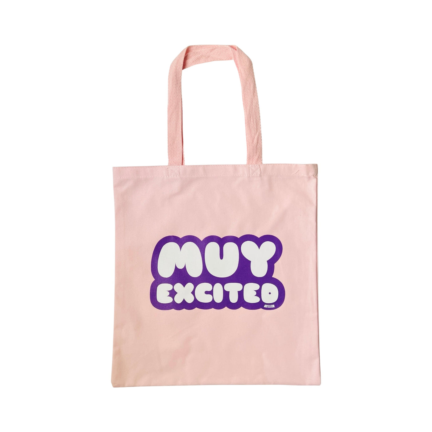 Light pink canvas tote bag with the phrase Muy Excited in white lettering outlined in purple.