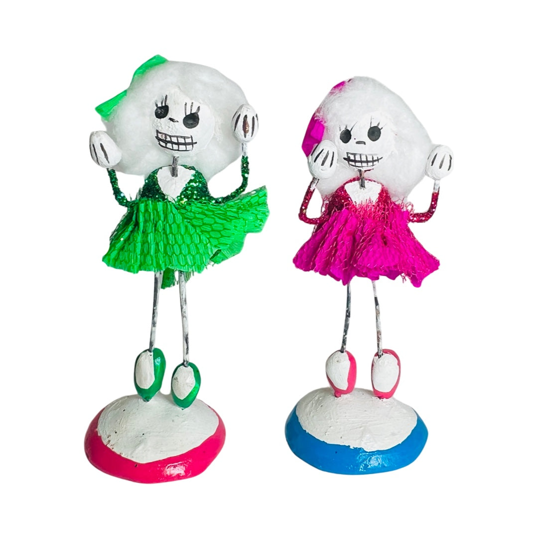 set of clay and wire calavera dancers wearing green and pink outfits.