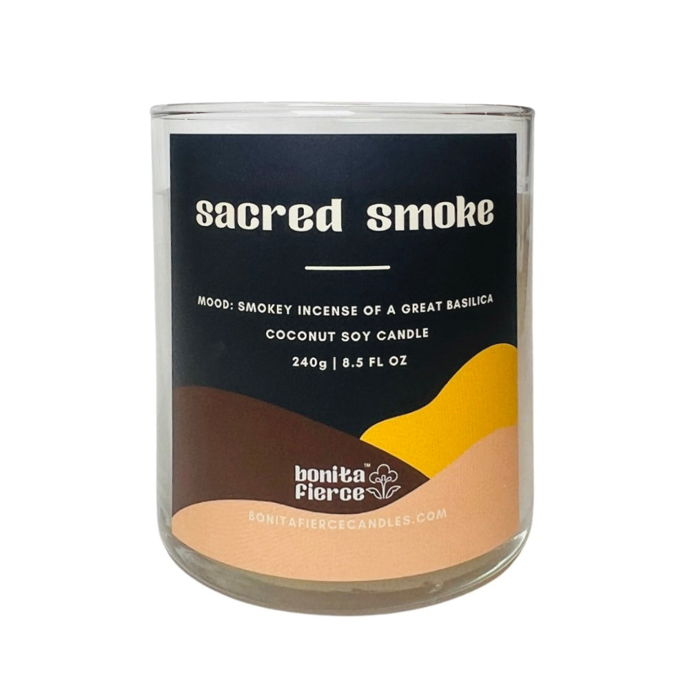 8.5 oz glass sacred smoke candle with a branded label with shades of brown, black and yellow