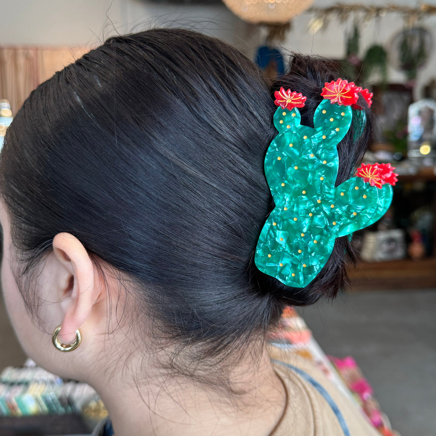 Green prickly pear cactus-shaped hair claw clip with red flowers and gold accents.