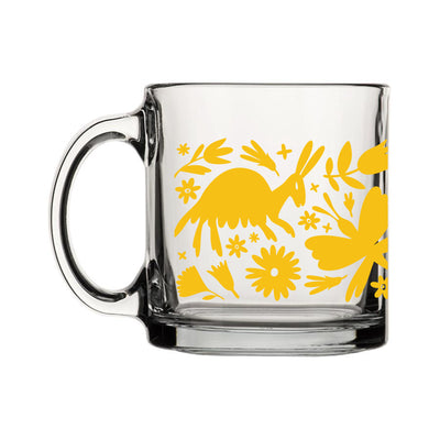 Back view of clear glass mug featuring a wraparound print of a yellow otomi design