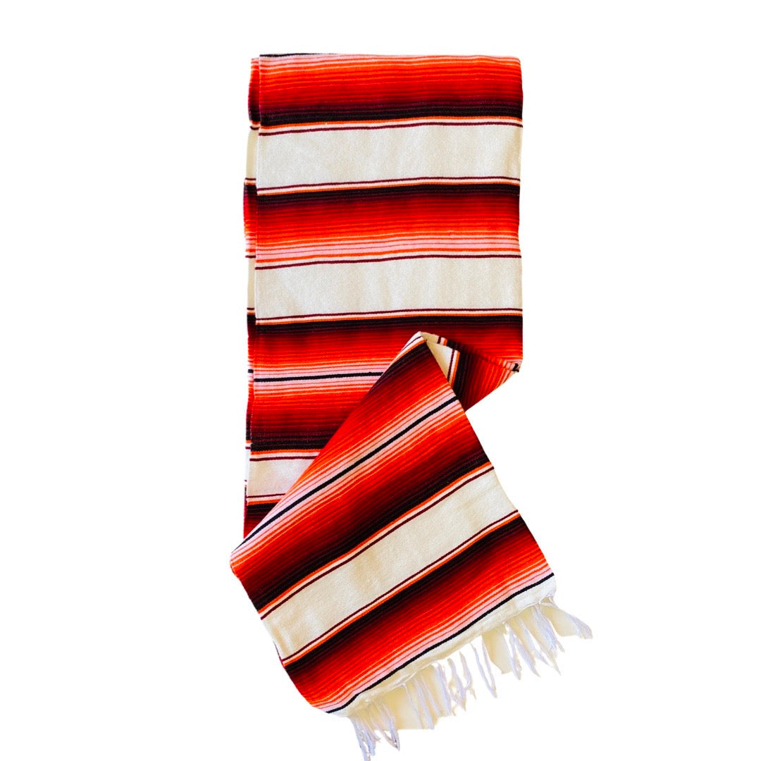Red and white serape striped blanket folded in half.