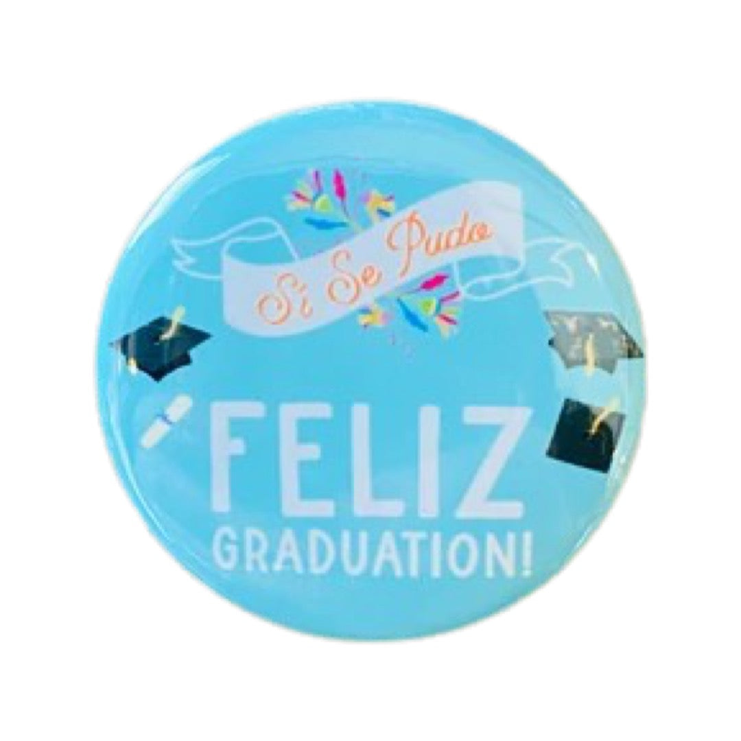 Light blue round pin with the phrase Feliz Graduation and features two graduation caps and a banner with the phrase Si Se Puede.