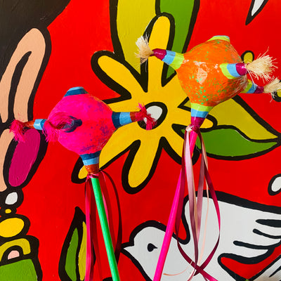 Piñata Paper Mache Shakers with colorful ribbons (Style 1) pictured in front of Artelexia Frida mural.