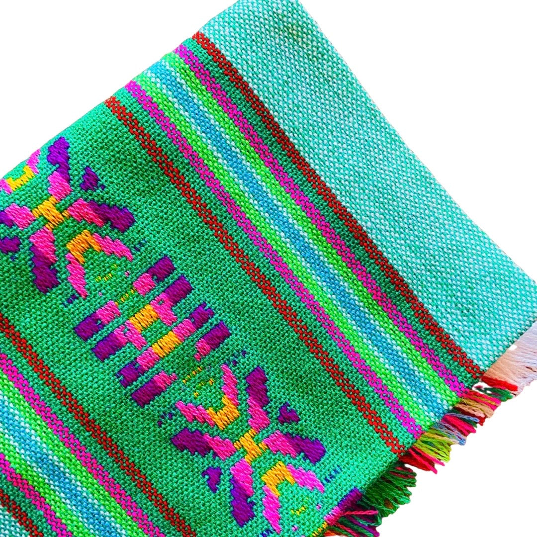 Close up of green Mexican Servilleta. Design features multicolored stripes with pattern.