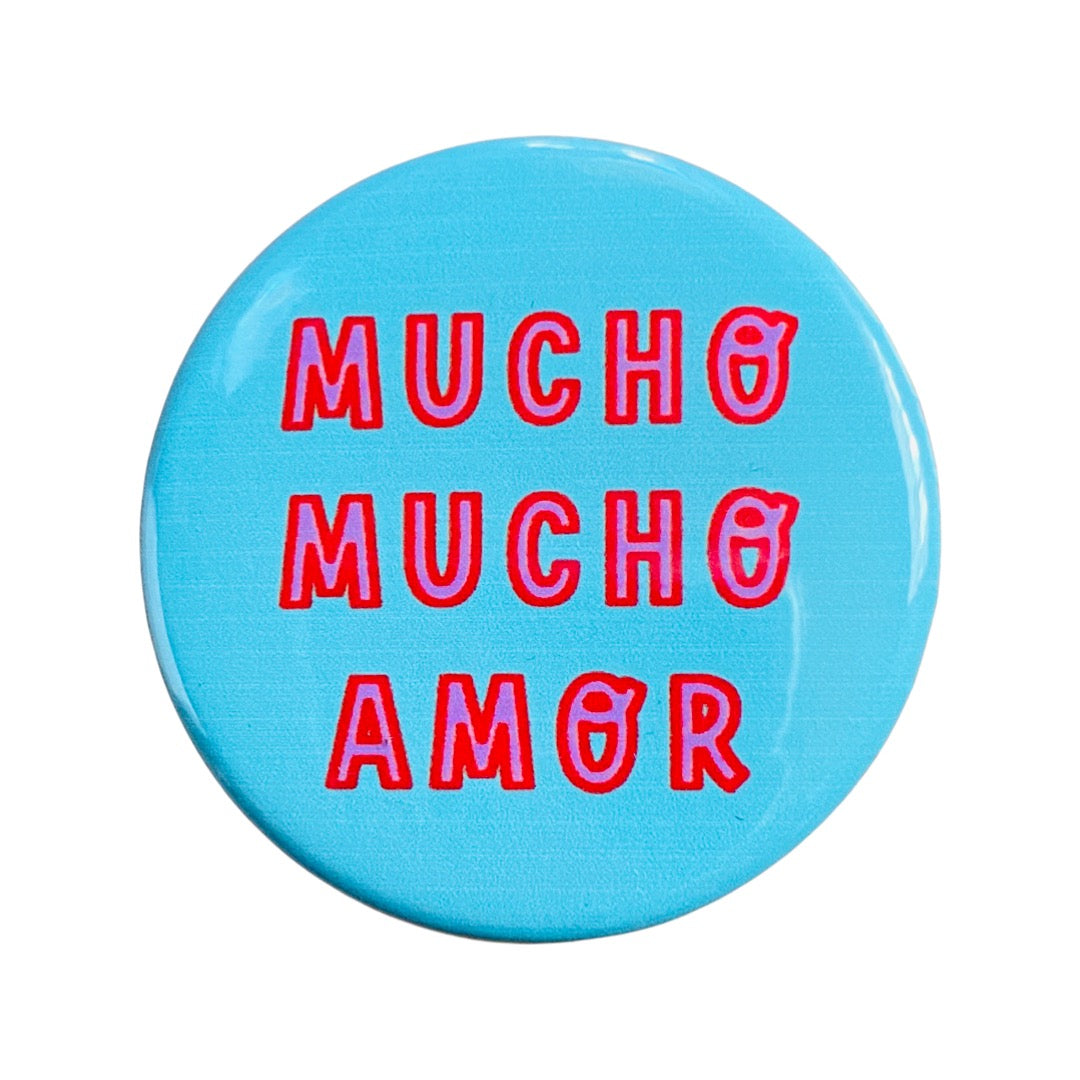 Teal Round pin button with the phrase Mucho Mucho Amore in pink and red lettering