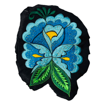 Woven blue flower embroidered on black fabric.
