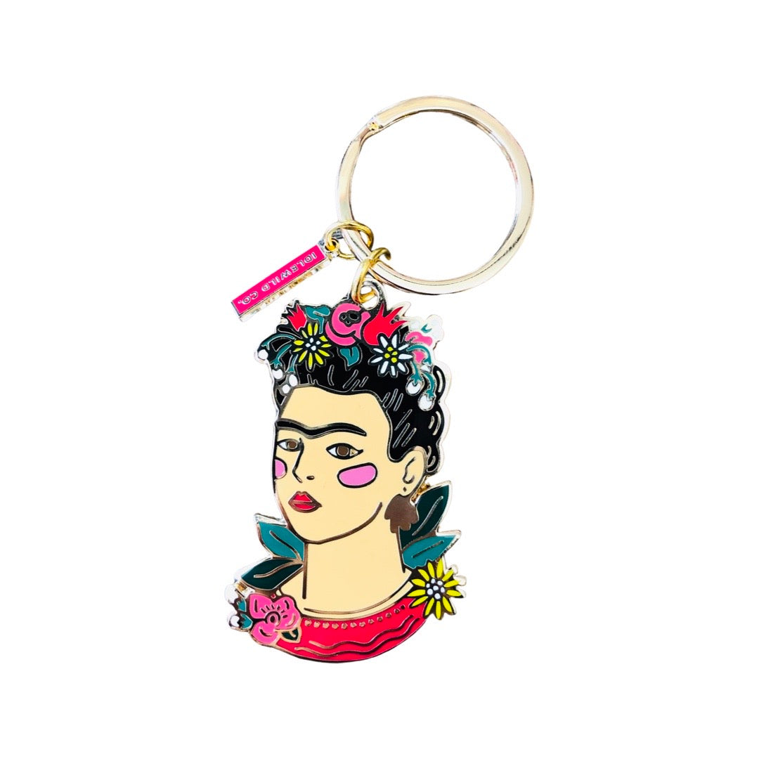 Frida Kahlo enamel keychain with gold accents. Frida wears a flower crown and is surrounded by plants.