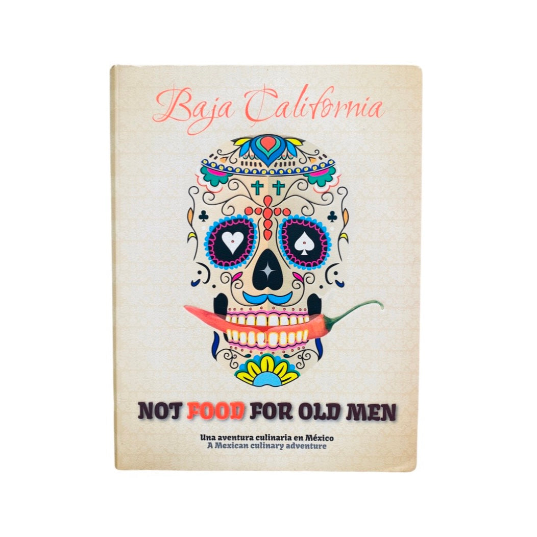 The image displays the cover of a book titled 'Baja California - Not Food for Old Men'. The cover features a flexicover design with a vibrant and colorful illustration of a skull, stylized in the manner of a calavera, with intricate patterns and a chili pepper.