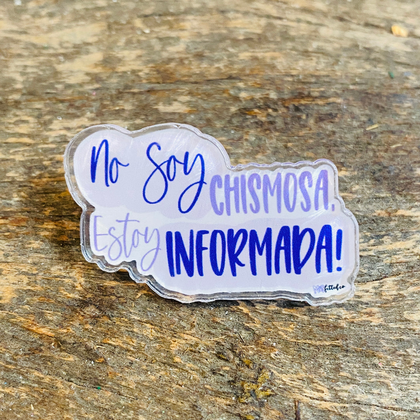 Pastel blue pin that reads "No soy chismosa, soy informada!" shown on a wooden table. 