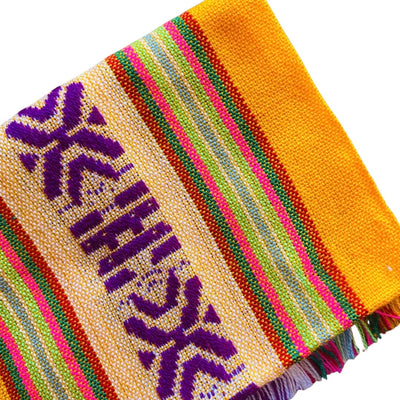 Close up of yellow Mexican Servilleta. Design features multicolored stripes with pattern.