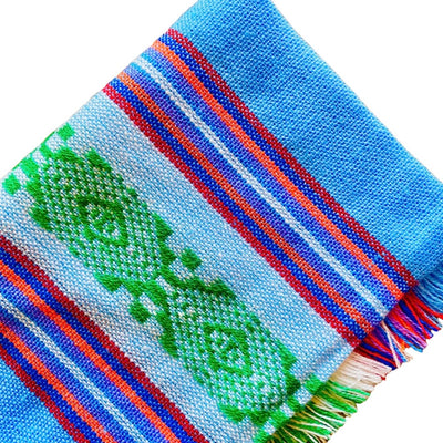Close up of blue Mexican Servilleta. Design features multicolored stripes with pattern.