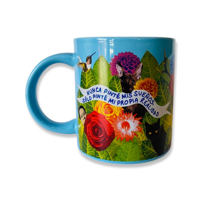 Side view of blue Frida dream mug features phrase, "Nunca pinte mis suenos, solo pinte mi propia realidad." Design features animals, colorful flowers, and green leafs.