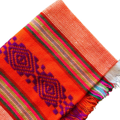 Close up of orange Mexican Servilleta. Design features multicolored stripes with pattern.