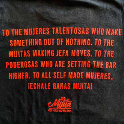 Back of black, "Self Made Mujer" t-shirt with red detail. Back of shirt reads, "To the mujeres talentosas who make somethng out of nothing. To the mijitas making jefa moves. To the poderosas who are setting the bar higher. To all self made mujeres. Echale ganas mijita!"