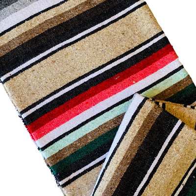 Close up view of sand colored serape striped blanket folded in half.