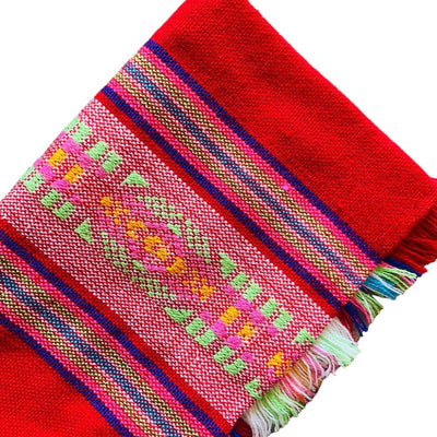 Close up of red Mexican Servilleta. Design features multicolored stripes with pattern. 