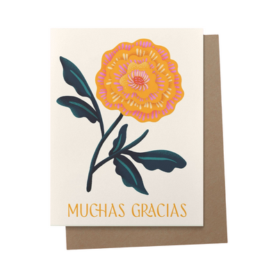 brown envelope behind a cream card with an illustration of a pink and orange flower and the phrase muchas gracias in orange lettering