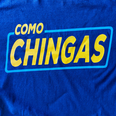 Close up men's blue, "Como Chingas" phrase t-shirt with yellow detail.