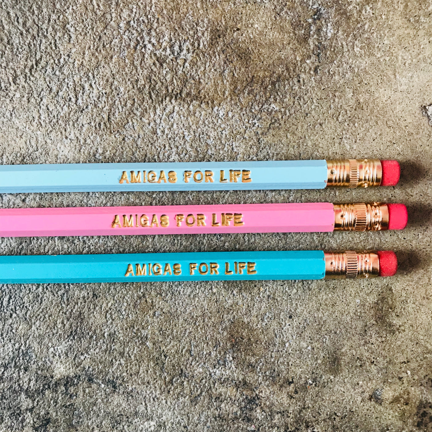 Amigas for life phrase pencils in light blue, light pink, and turquoise. 