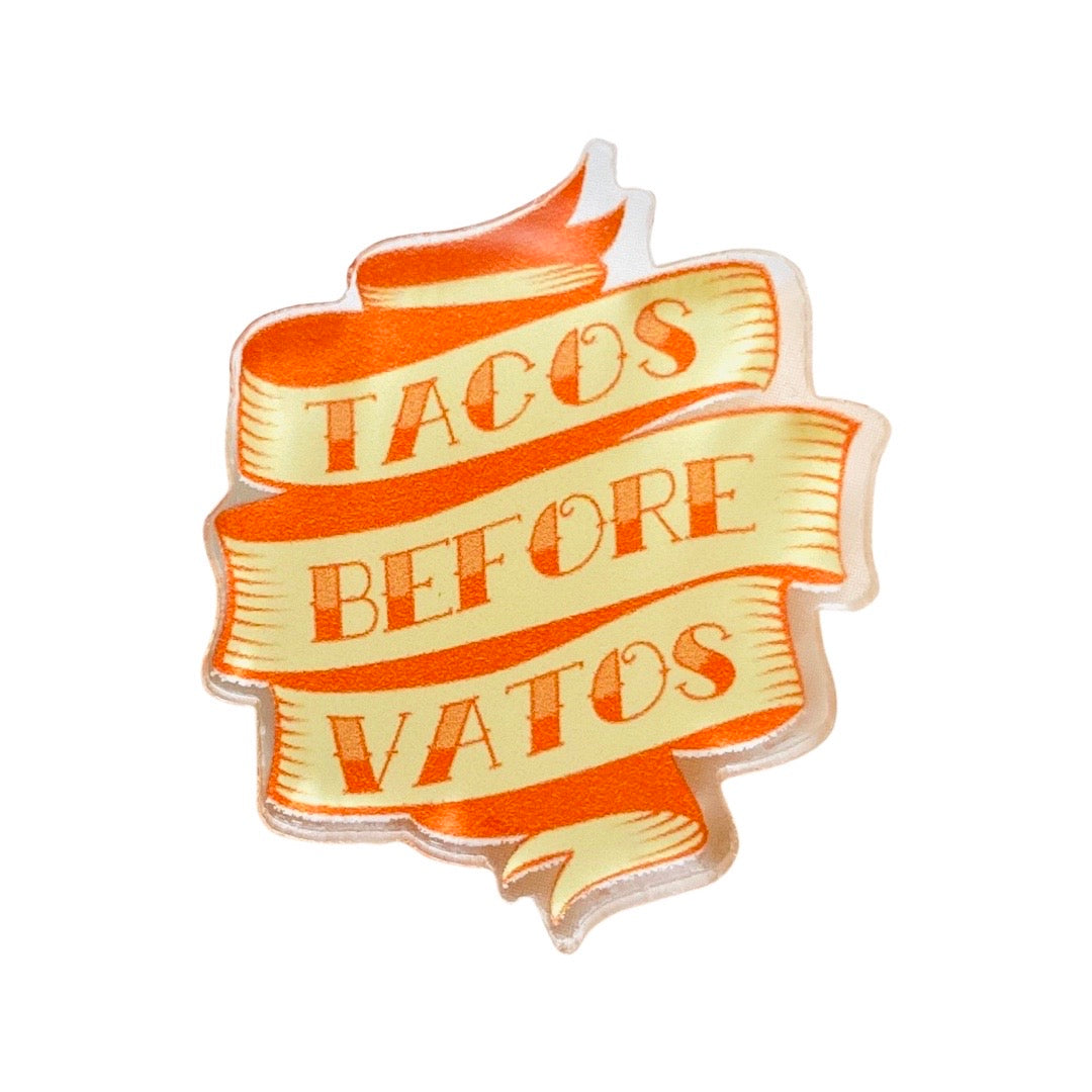 Cream banner pin with red text that reads "Tacos before vatos".