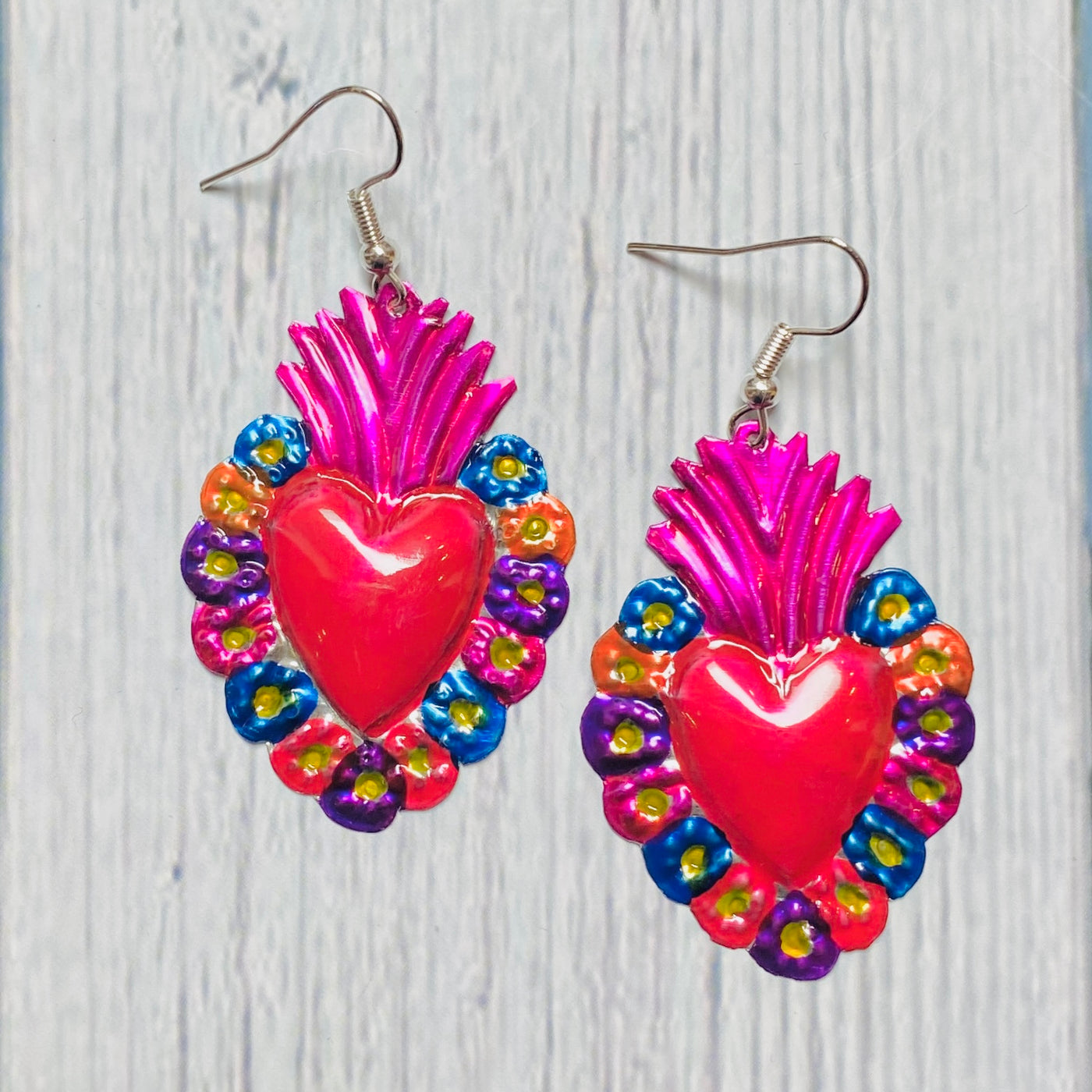 Colorful tin sacred heart earrings with flowers around the heart.