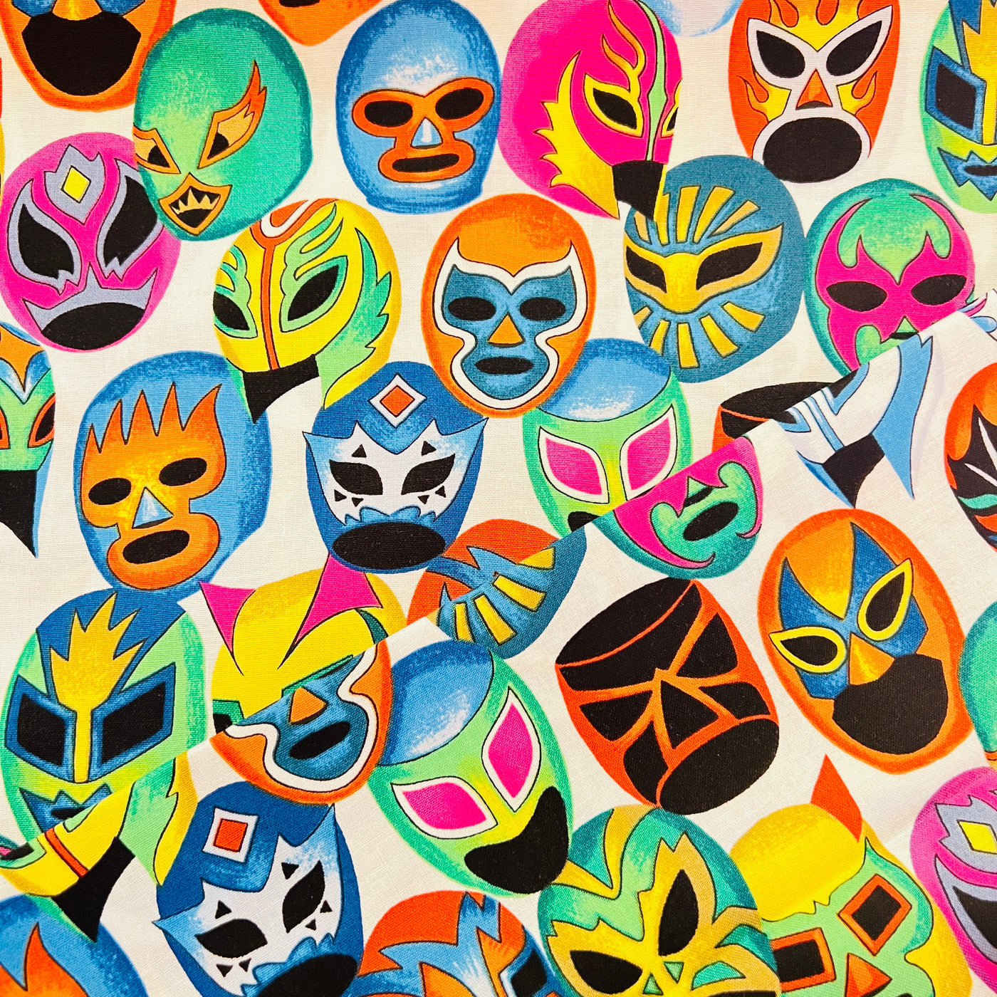 Fabric with a luchador mask pattern. All the masks are various designs and colors.