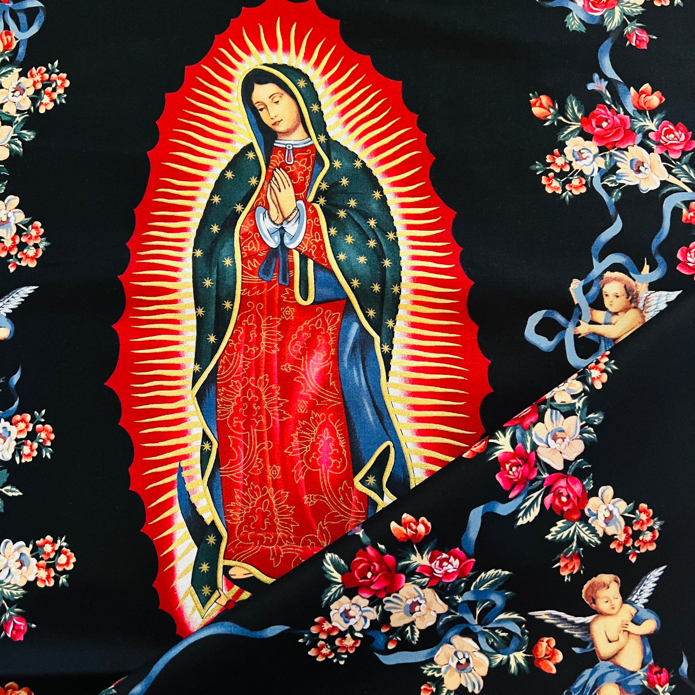 Image of the Virgin of Guadalupe on a black background and features angels and flowers throughout the design.