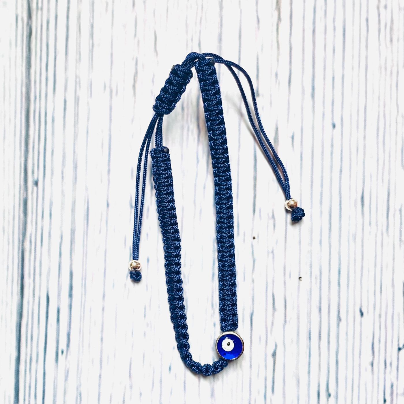Blue braided string bracelet with evil eye charm.