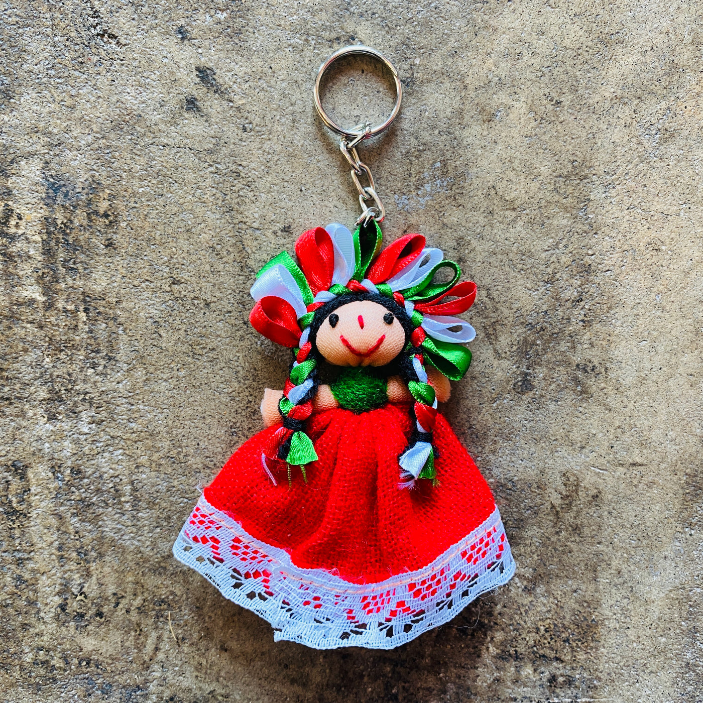 Small Mexican woven rag doll in red, white and green colors on a keychain.