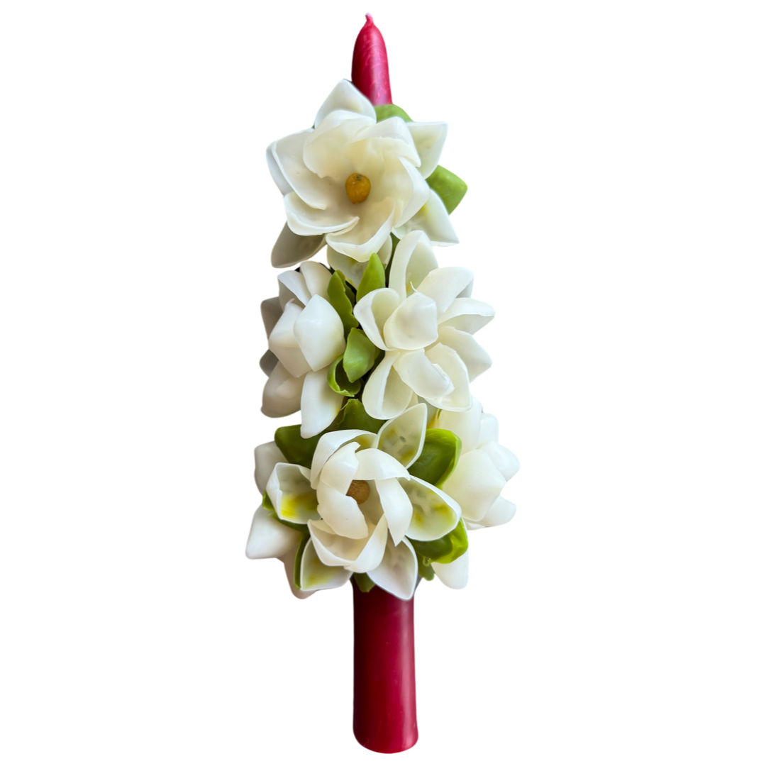 red tapered candle decorated with ivory flowers & green leaves
