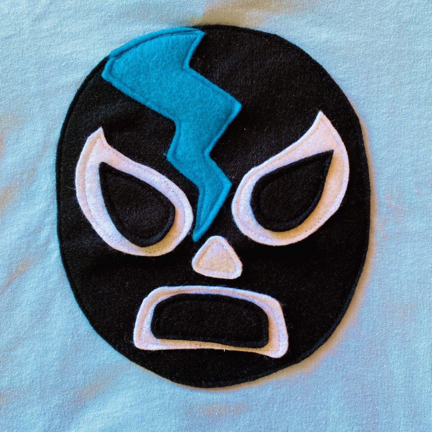 Close up of hand-stitched Luchador design on blue kid's t-shirt.