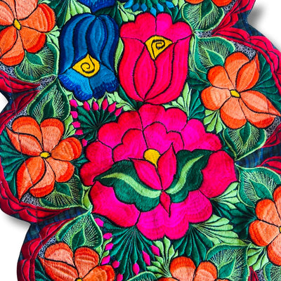 Close-up picture of a table runner that features brightly colored embroidered flowers.